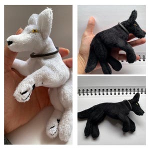 May include: A plush toy dog in white with a black collar and yellow eyes. The dog is lying down with its legs extended. Another image shows a black plush dog with a gray collar.