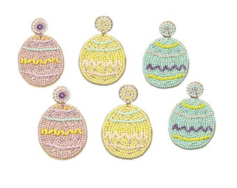 May include: Six pairs of beaded Easter egg earrings. The earrings are in various colors, including pink, yellow, green, and purple. Each earring is shaped like an egg and has a beaded design.