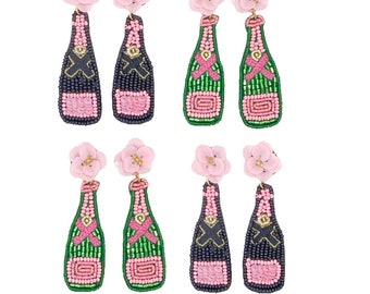 May include: A set of eight beaded champagne bottle earrings. The earrings feature pink and black or green and black bottle designs with pink flower accents. The bottles have sequin details and gold accents. The earrings are on a white background.