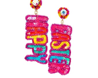 May include: A pair of dangle earrings with the word "YOURS" spelled out in rainbow-coloured sequins. The earrings are made of gold metal and have a pink base.