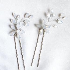 May include: Two silver hair pins with white opal flower accents. The flowers are made of small, teardrop-shaped opals and are arranged in a delicate, leafy design.