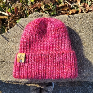 May include: A pink knitted beanie with a brown leather tag that says "Belle & Joy".