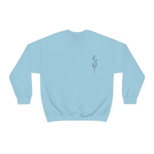 May include: A light blue sweatshirt with a small, simple line drawing of a flower on the left chest.