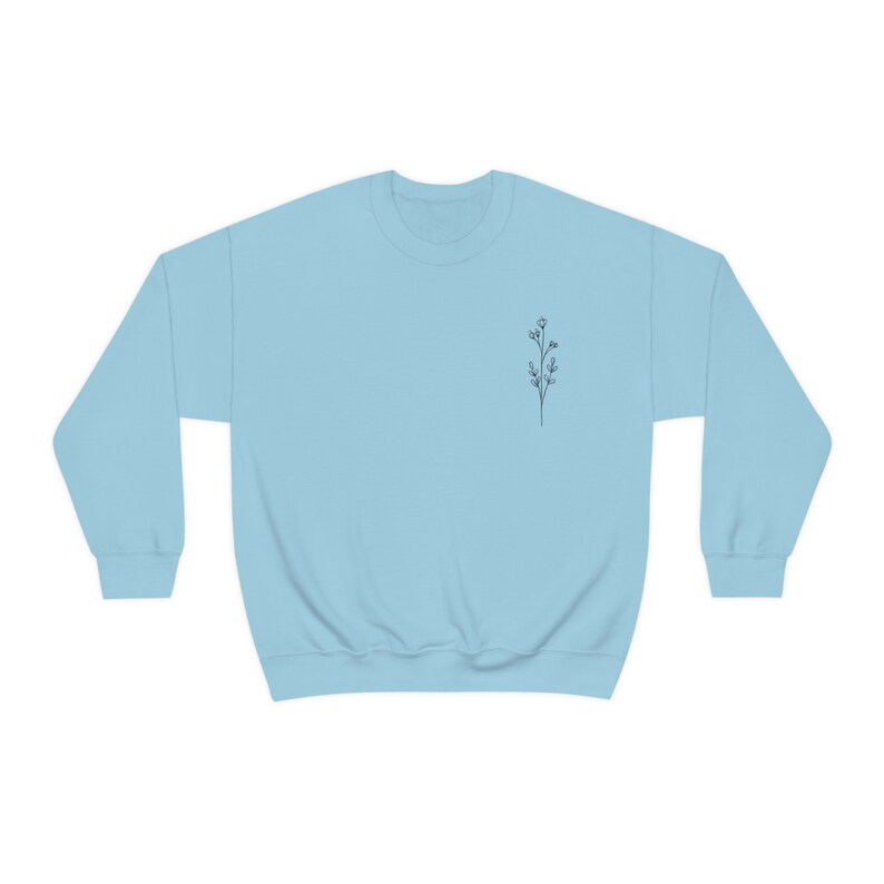 May include: A light blue sweatshirt with a small, simple line drawing of a flower on the left chest.