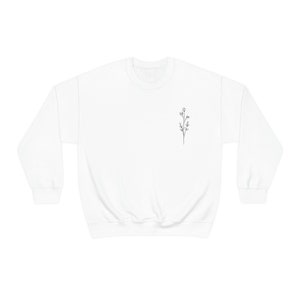 May include: White crewneck sweatshirt with a small black line drawing of a flower on the left chest.
