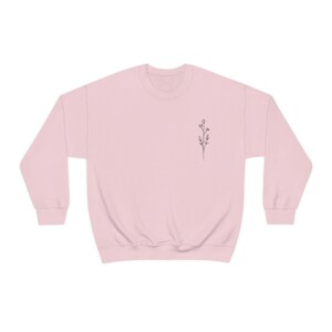 May include: A pink sweatshirt with a small floral design on the left chest.