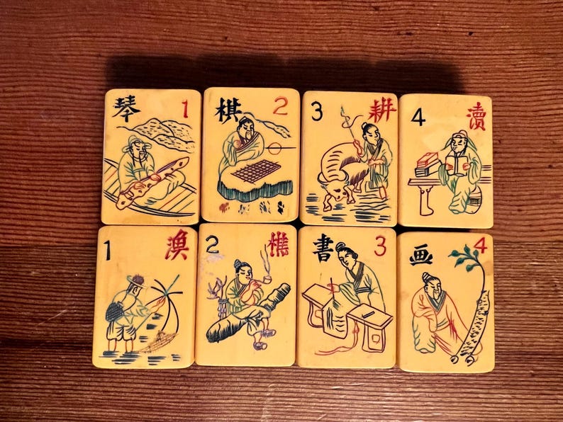 K&ouml;nnte beinhalten: Acht Vintage-Mahjong-Steine in Elfenbeinfarbe mit schwarzen und farbigen Illustrationen von Figuren und Szenen. Jede Kachel hat eine Nummer von 1 bis 4 und chinesische Schriftzeichen. Die Kacheln sind auf einer Holzoberfl&auml;che angeordnet.