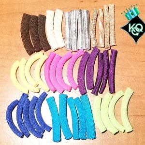 May include: Assortment of colorful fabric strips in various shapes and sizes. The strips are arranged in rows, with each row featuring a different color. The colors include yellow, pink, purple, blue, green, and brown.