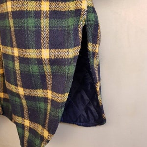 May include: A garment featuring a dark navy blue, forest green, and bright yellow plaid pattern. The outer layer has a textured, wool-like appearance, while the interior lining is a solid dark navy blue fabric with a quilted diamond stitch pattern.
