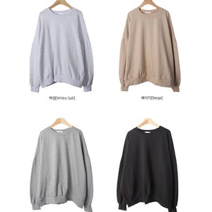 May include: Four sweatshirts in different colours: white salt, beige, grey, and black. The sweatshirts have a relaxed fit and a round neckline.