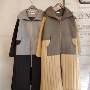 May include: Two long hooded coats with zipper closures. The coat on the left is gray and black, and the coat on the right is green and tan.