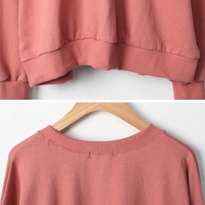 May include: A dusty rose coloured long-sleeved sweatshirt with a crew neck.