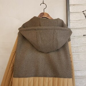 Puede incluir: Una chaqueta marr&oacute;n con capucha y forro acolchado beige. La chaqueta tiene una capucha grande y una cremallera.