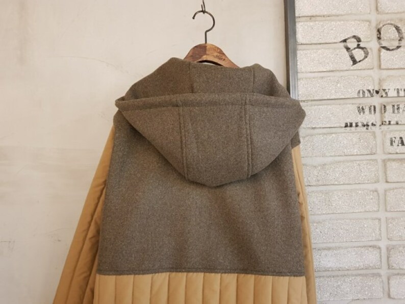 Puede incluir: Una chaqueta marr&oacute;n con capucha y forro acolchado beige. La chaqueta tiene una capucha grande y una cremallera.