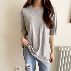 Puede incluir: Una camiseta gris de gran tamaño con mangas cortas. La camiseta está hecha de una tela suave y cómoda y tiene un corte holgado.