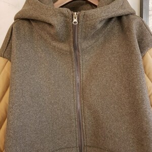 Puede incluir: Una chaqueta marr&oacute;n con capucha, cierre de cremallera y tejido acolchado marr&oacute;n en las mangas.