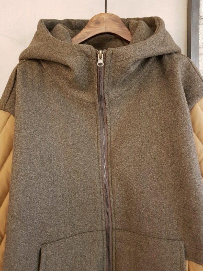 Puede incluir: Una chaqueta marr&oacute;n con capucha, cierre de cremallera y tejido acolchado marr&oacute;n en las mangas.