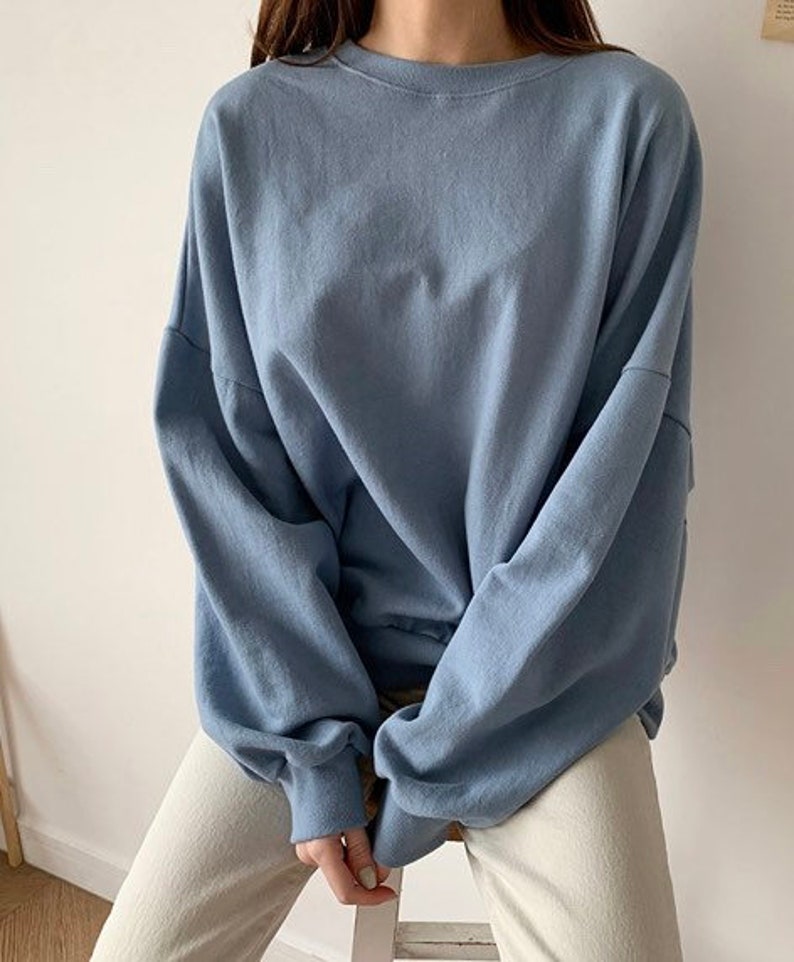 May include: A light blue long-sleeved shirt with a relaxed fit and a round neckline.