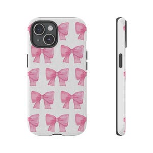 May include: A white phone case featuring a repeating pattern of pink watercolor bows. The bows are evenly spaced across the case's surface. The case has a black camera module and black side buttons.