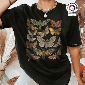 May include: Black oversized t-shirt with a vintage illustration of various butterflies and moths. The shirt features a variety of colors and patterns, including brown, green, yellow, and black.