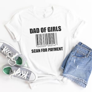 May include: White t-shirt with black text that reads "Dad of Girls" and a barcode with the number "640509 040147" below it. The text "Scan for Payment" is below the barcode.