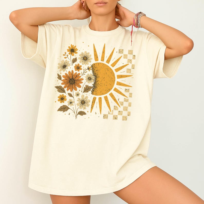 A woman wearing a white t-shirt with a sun and flower design on it.