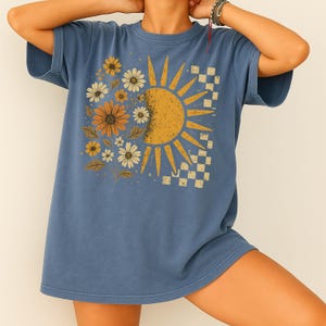 A person wearing a blue t-shirt with a sun and flower design.