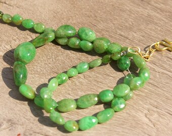 May include: A green gemstone necklace with a gold clasp. The necklace is made of oval-shaped beads.