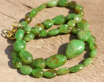 May include: A green gemstone necklace with a large, teardrop-shaped pendant. The necklace is made of smooth, oval-shaped beads.