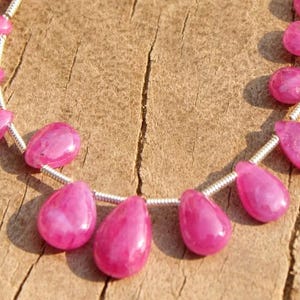 K&ouml;nnte beinhalten: Eine Kette aus rosafarbenen Edelsteinperlen, jede Perle hat eine Tropfenform und ist auf einem Silberdraht aufgef&auml;delt.