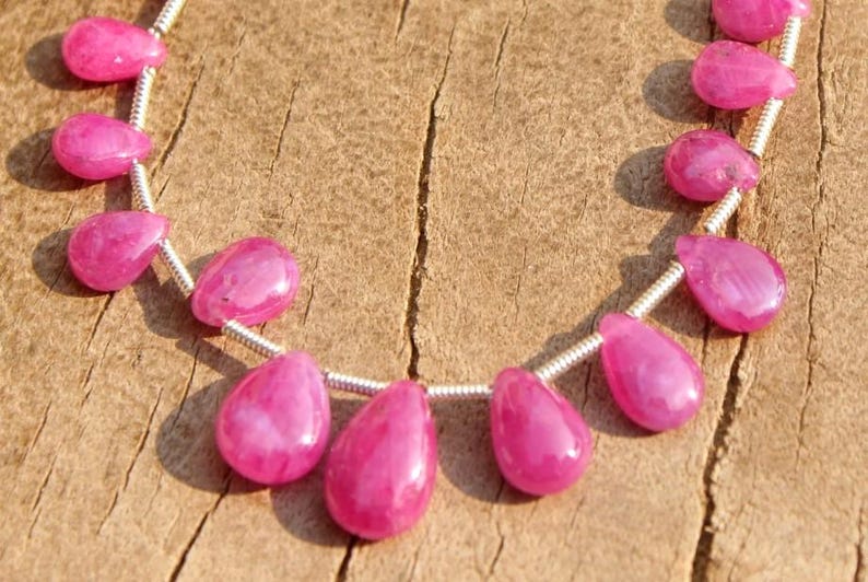K&ouml;nnte beinhalten: Eine Kette aus rosafarbenen Edelsteinperlen, jede Perle hat eine Tropfenform und ist auf einem Silberdraht aufgef&auml;delt.