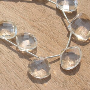 May include: A strand of clear quartz gemstone beads, each bead is faceted and has a unique shape. The beads are strung on a silver wire.