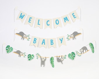 Puede incluir: Tres guirnaldas de banderines con temática de perezosos. La pancarta superior dice "WELCOME" en letras azules sobre fondo blanco. La pancarta del medio dice "BABY" en letras azules sobre fondo blanco. La pancarta inferior tiene perezosos colgando de ramas con hojas verdes.