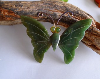 May include: A green jade butterfly brooch with gold accents. The butterfly has detailed wings and a delicate body.