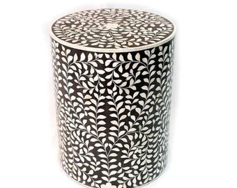 May include: A round, black and white bone inlay side table with a leaf pattern. The table is approximately 18 inches tall and 16 inches in diameter.