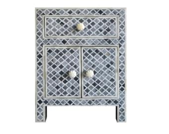 May include: A gray and white nightstand with a geometric pattern. It has one drawer and two doors with white knobs.