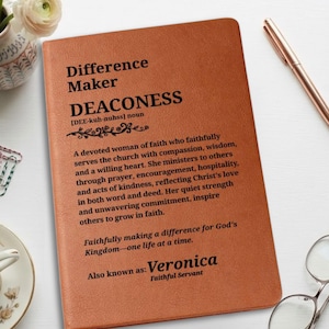 Peut inclure: Un carnet à couverture en cuir beige avec du texte imprimé en noir définissant le mot diaconesse. Le texte comprend une prononciation phonétique, un paragraphe descriptif sur la foi et le service, et le nom personnalisé Veronica en bas.