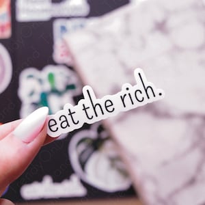 May include: A white sticker with black text that reads "eat the rich."