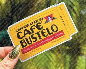 May include: A yellow and white sticker with the text "CAFFEINATED BY CAFE BUSTELO" in black. The sticker is shaped like a coffee package and has the text "Cafe Espresso Molido. Espresso Ground Coffee" and "NET WT 10 OZ (283g)" in black.