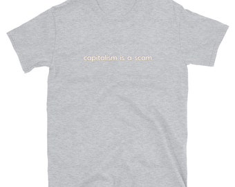 May include: A heather grey t-shirt with the text "capitalism is a scam" printed in a light peach colour.