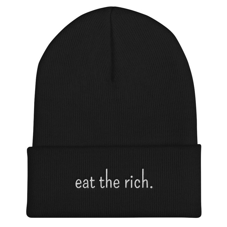 Może przedstawiać: Czarna czapka z daszkiem z haftem "eat the rich." w kolorze białym z przodu.