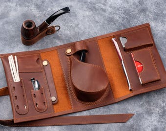 May include: A brown leather tobacco pouch with multiple pockets and compartments. The pouch has a strap and a separate pocket for a pipe.