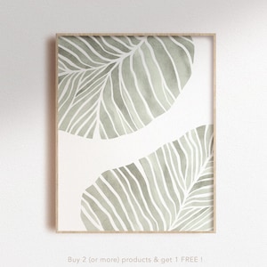 Op de afbeelding: Een ingelijst print met een minimalistisch ontwerp met twee groene aquarelbladeren met witte lijnen. De tekst "Buy 2 (or more) products & get 1 FREE!" en "nunu PRINT SHOP" staat onderaan de print.