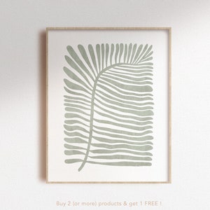 Könnte beinhalten: Ein gerahmter Druck eines stilisierten grünen Palmblattes auf weißem Hintergrund. Der Druck hat einen Holzrahmen und den Text "Buy 2 (or more) products & get 1 FREE!" und "nunu PRINT SHOP" unten.