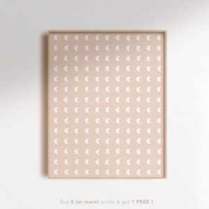 May include: A framed print with a repeating pattern of white crescent moons on a light pink background.