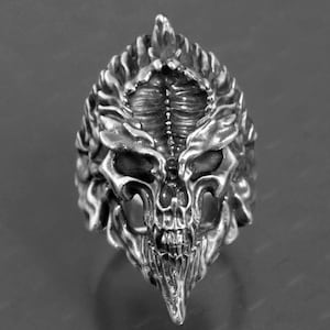 May include: A silver ring with a detailed skull design. The skull has a pointed crown and intricate details on the face and jaw.