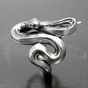 Op de afbeelding: Een zilveren slangenring met een gedetailleerd ontwerp. De slang is opgerold met zijn kop omhoog en zijn staart om zijn lichaam gewikkeld.