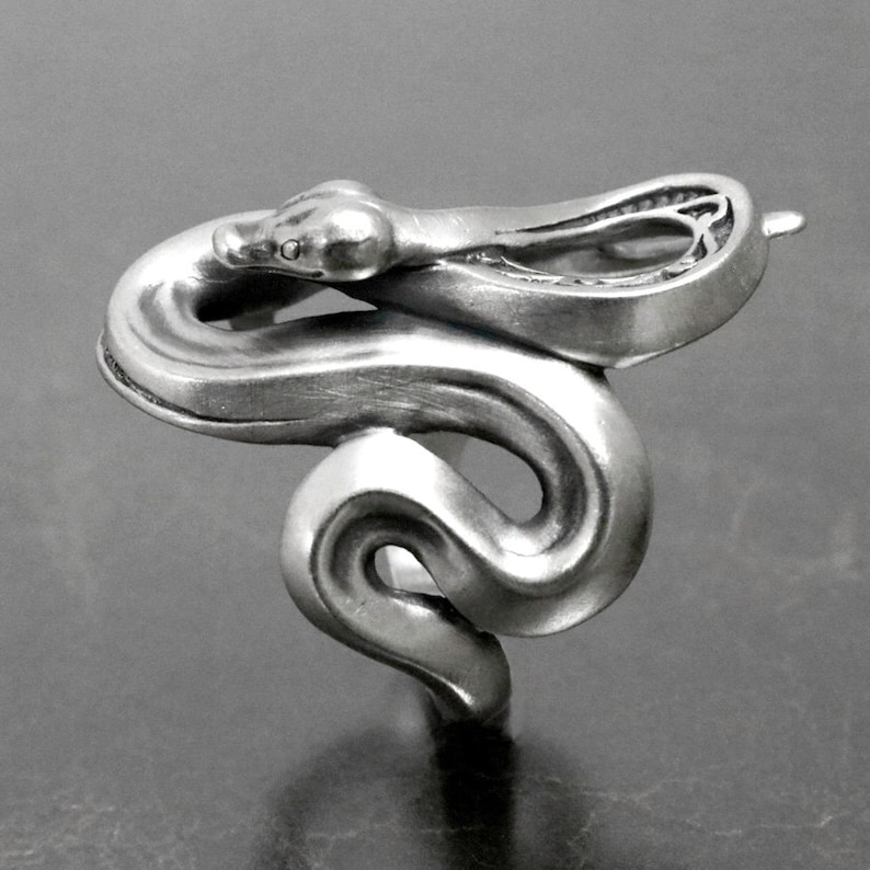 Op de afbeelding: Een zilveren slangenring met een gedetailleerd ontwerp. De slang is opgerold met zijn kop omhoog en zijn staart om zijn lichaam gewikkeld.