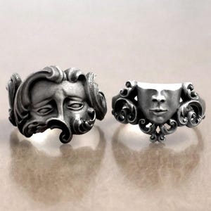 K&ouml;nnte beinhalten: Zwei silberfarbene Ringe mit detaillierten Gesichtsdesigns. Ein Ring zeigt ein volles Gesicht mit flie&szlig;endem Haar, der andere ein teilweises Gesichtsdesign. Beide Ringe haben aufwendige, verzierte Details und zeigen eine gotische oder Vintage-&Auml;sthetik.
