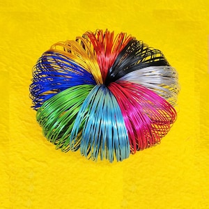 May include: A colorful set of metal rings, stacked and coiled together. The rings are in various colors, including red, blue, green, yellow, and silver.
